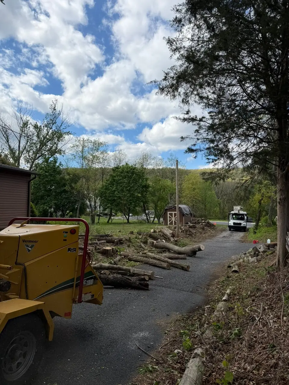 Driveway access to a backyard job with a chipper parked
